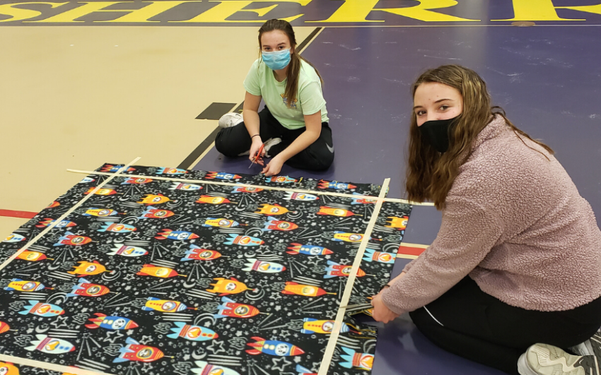 Chapter members creating tie blankets to donate.