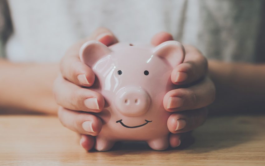 A piggy bank with hands wrapped around it