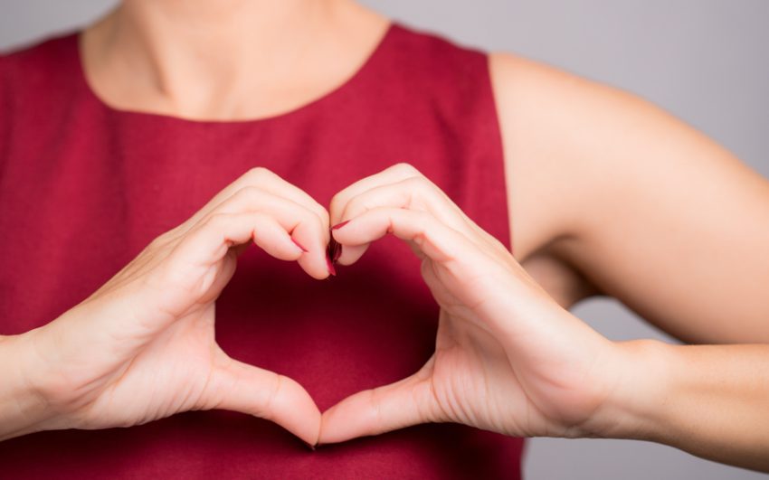 A woman holding up her hands to form a heart