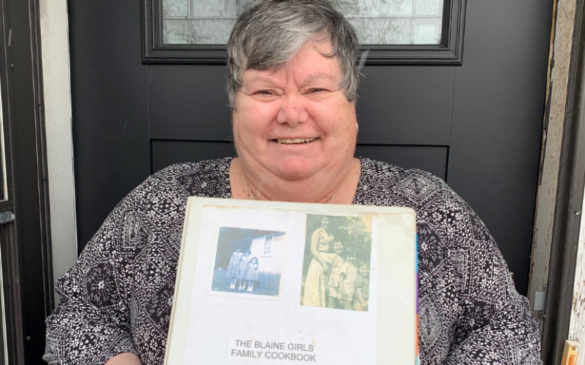 Member Sandy Bechtold holding her beloved copy of the Blaine Girls Family Cookbook.