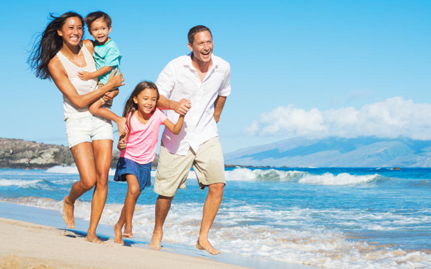 Family running and smiling on the beach