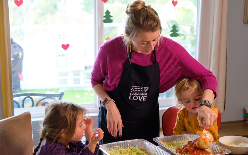 Nation of Neighbors recipient Rhiannon Menn making lasagna with her two young daughters.